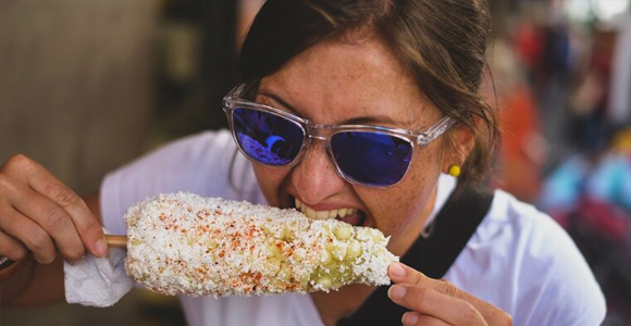 woman biting into an elote