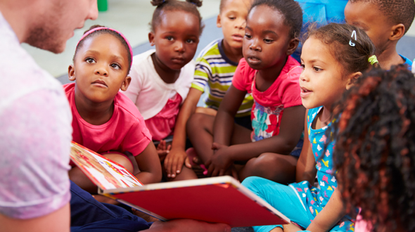 young man reading to a bunch of school children